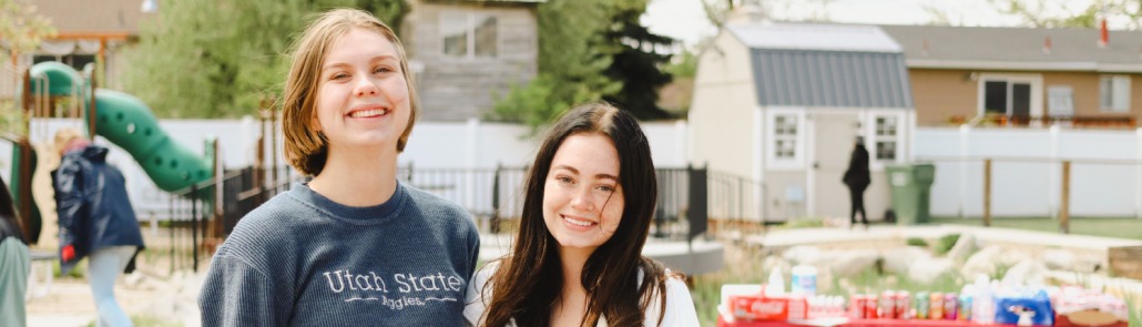 two female USU student volunteers standing together and smiling