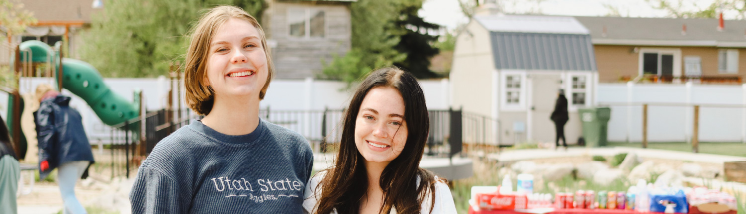 two female USU student volunteers standing together and smiling