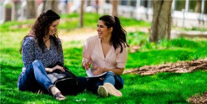 Mother and daughter sitting outside in the sunshine while talking and laughing