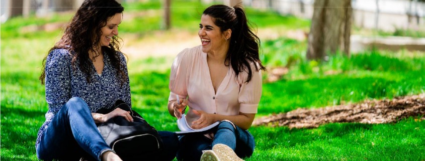 Mother and daughter sitting outside in the sunshine while talking and laughing